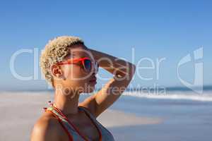 Beautiful woman in sunglasses looking away on beach in the sunshine