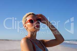 Beautiful woman in sunglasses looking away on beach in the sunshine