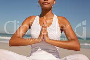 Woman doing yoga at beach in the sunshine