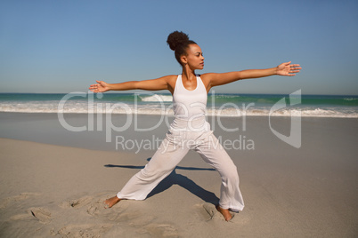 Beautiful woman doing yoga at beach in the sunshine