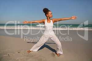 Beautiful woman doing yoga at beach in the sunshine