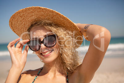 Woman in hat and sunglasses looking at camera on the beach