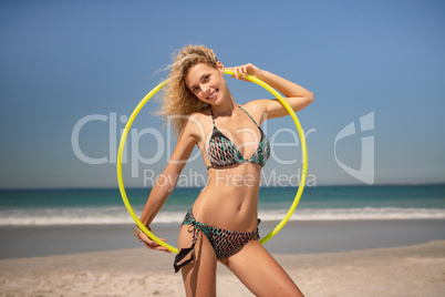 Beautiful woman standing with hula hoop ring on the beach