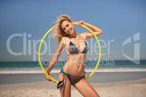 Beautiful woman standing with hula hoop ring on the beach