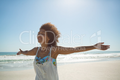 Woman standing with arms outstretched on the beach