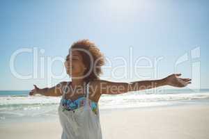 Woman standing with arms outstretched on the beach