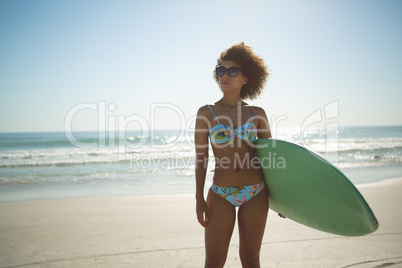 Woman standing with surfboard on the beach