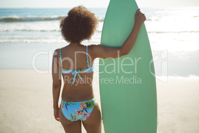 Woman standing with surfboard on the beach