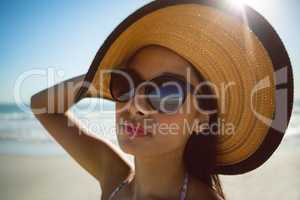 Woman in hat and sunglasses standing on the beach