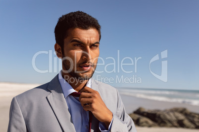 Young Businessman removing his tie on the beach