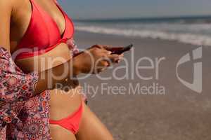 Woman in bikini using mobile phone on the beach