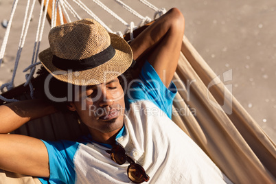 Man with hat sleeping in a hammock on the beach