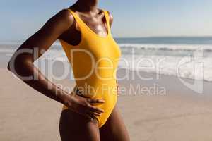 Woman in swimwear standing with hands on hip on the beach