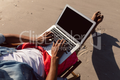 Man using laptop while relaxing in a beach chair on the beach