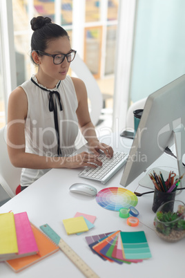 Female graphic designer working on computer at desk in a modern office