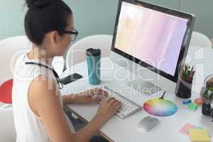 Female graphic designer working on computer at desk in a modern office