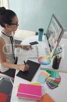 Female graphic designer using graphic tablet at desk in a modern office