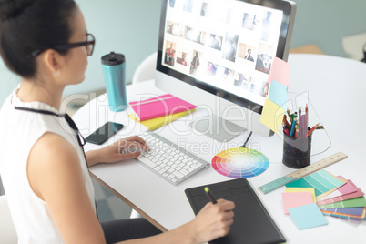 Female graphic designer using graphic tablet at desk in a modern office