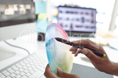 Female graphic designer working with color swatch at desk in a modern office