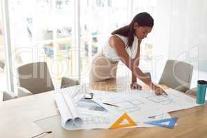 Female architecture working on blueprint on table in a modern office