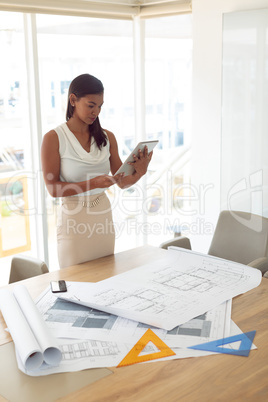 Female architecture using digital tablet at table in a modern office