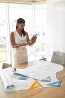 Female architecture using digital tablet at table in a modern office