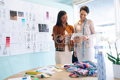 Female fashion designers discussing over digital tablet in a modern office