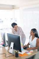 Female graphic designers talking with each other at desk in a modern office