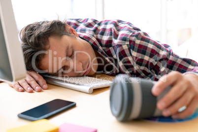 Male graphic designer sleeping on desk in a modern office