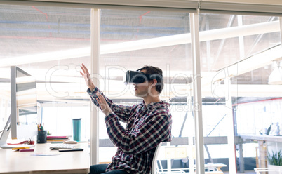 Male graphic designer using virtual reality headset at desk