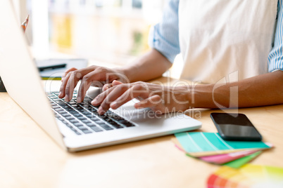 Female graphic designer using laptop at desk