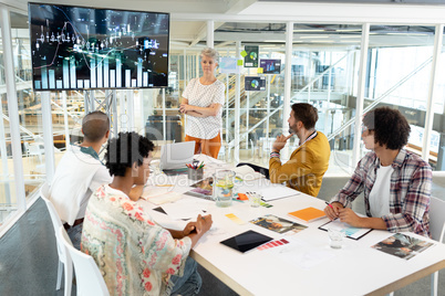 Businesswoman giving presentation on screen during meeting in a modern office