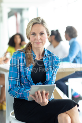 Businesswoman with digital tablet looking at camera at conference room in a modern office