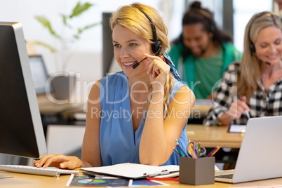 Female customer service executive talking on headset and working on computer in a modern office
