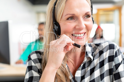 Female customer service executive looking away while talking on headset in a modern office
