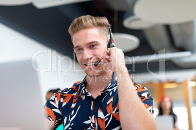 Male customer service executive talking on headset in a modern office