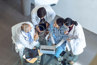 Medical team discussing over digital tablet at the table in hospital