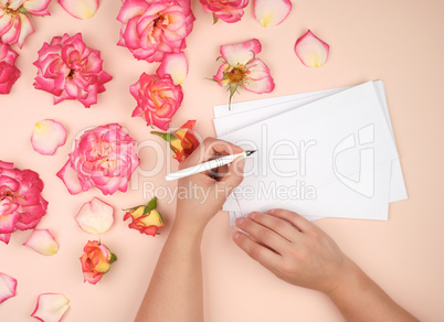 girl holds in her left hand a white pen and signs envelopes on a