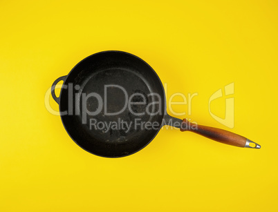 empty round black cast-iron frying pan with wooden handle