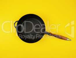 empty round black cast-iron frying pan with wooden handle