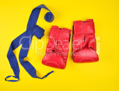 pair of red leather boxing gloves and blue textile bandage