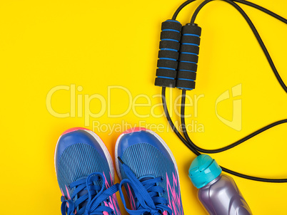 sports expander and water bottle and blue sneakers on a yellow b