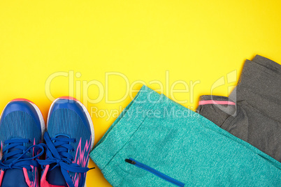 blue women's sneakers and clothes for sports on a yellow  backgr