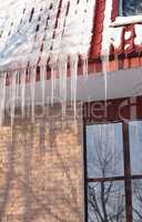 icicles on building roof at winter day