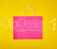 rectangular pink paper shopping bag with a white handle on a yel