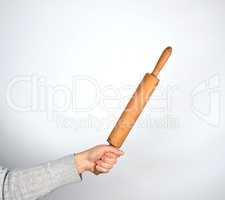 hand holding a wooden rolling pin on a gray background