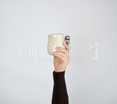 gray ceramic cup in female hand on a white background, hand rais