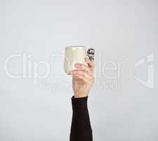 gray ceramic cup in female hand on a white background, hand rais