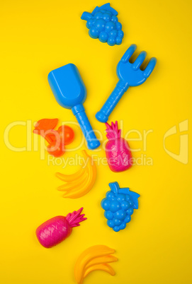 multicolored plastic toys fruits on a yellow  background