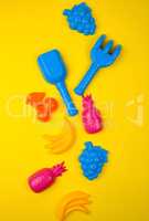 multicolored plastic toys fruits on a yellow  background